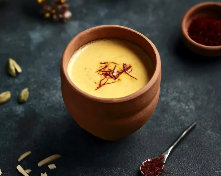 Safran Latte in einer braunen Tasse, dekoriert mit goldenen Safranfäden – aromatisches Milchgetränk aus Afghanistan.