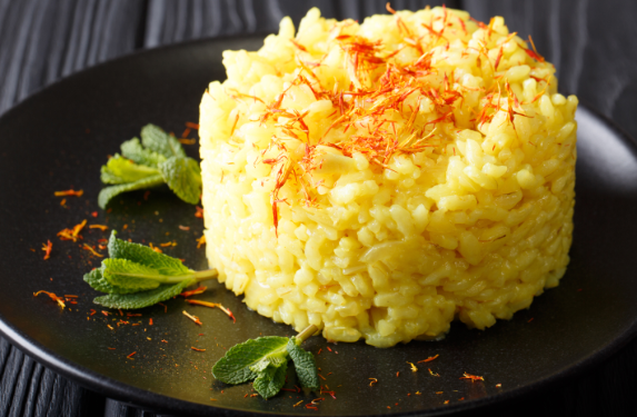 Safran Risotto – klassisches italienisches Risotto alla Milanese mit goldener Farbe, Parmesan und Safranfäden auf dunklem Teller.