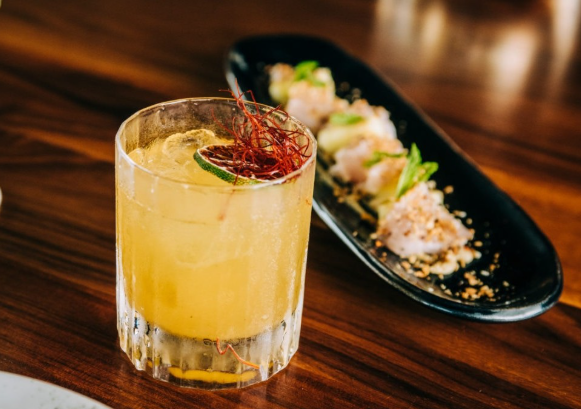 Japanischer Yuzu-Honig-Safran-Drink in einem Glas mit Eiswürfeln, dekoriert mit Zitrusschalen und goldenen Safranfäden – erfrischendes asiatisches Getränk.