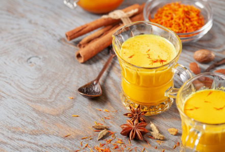 Goldene Safran Milch mit Honig in einem Glasbecher, dekoriert mit Zimtstange und Safranfäden – traditionelles afghanisches Getränk für Ruhe und Entspannung.