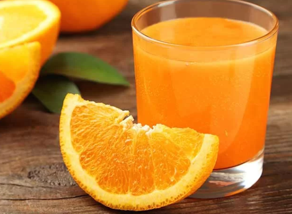 Safran Orangewasser in einem Glas mit heller goldgelber Farbe, zubereitet aus Safranfäden und frischen Orangenscheiben als koffeinfreies Sommergetränk.