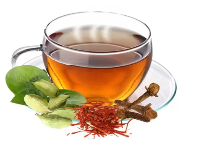 Safran Tee mit Gewürzen in einer Tasse, goldgelbe Farbe mit Safranfäden, Zimtstange und Kardamom als wärmendes Wintergetränk.