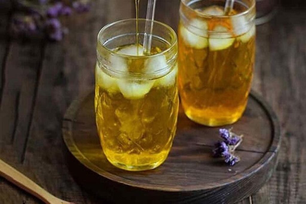 Kaltes Safran Wasser in einem Glas mit heller goldgelber Farbe, serviert als leichtes Sommergetränk ohne Zusätze.