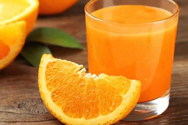 Safran Orangewasser in einem Glas mit heller goldgelber Farbe, zubereitet aus Safranfäden und frischen Orangenscheiben als koffeinfreies Sommergetränk.