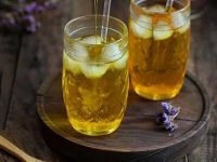 Kaltes Safran Wasser in einem Glas mit heller goldgelber Farbe, serviert als leichtes Sommergetränk ohne Zusätze.