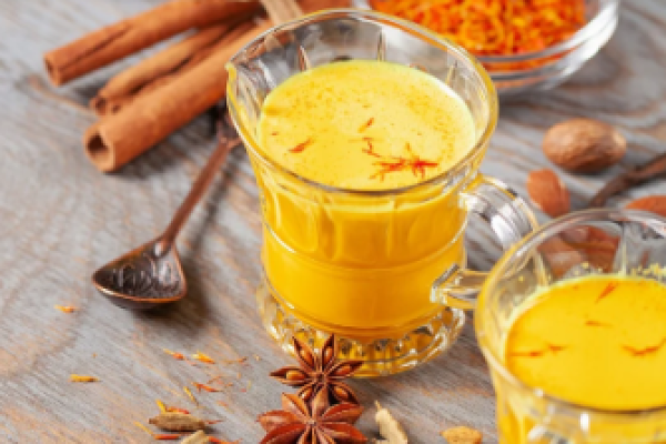 oldene Milch mit Safran und Honig in einem Glasbecher – cremiges, gesundes Getränk für innere Wärme.